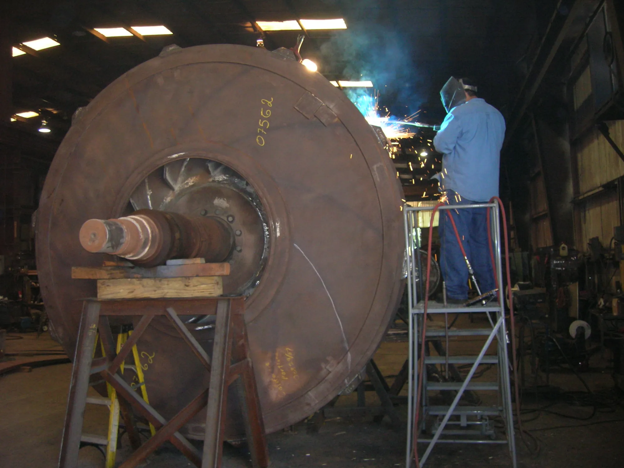 Barron Fan welder rebuilding a large centrifugal fan housing in the shop, sparks flying