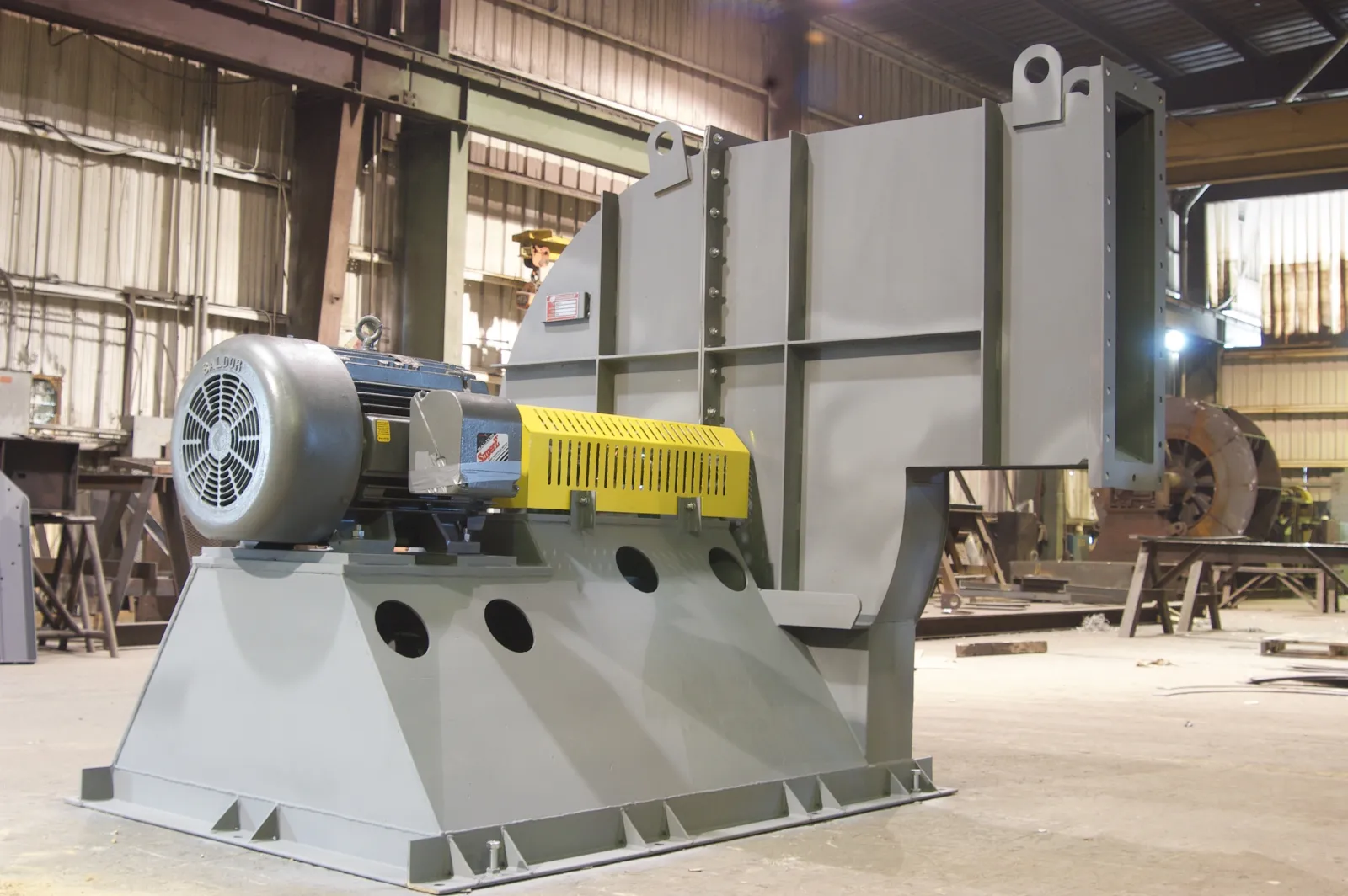 Complete new centrifugal fan with motor and yellow belt guard on a fabricated base in the Barron Fan shop